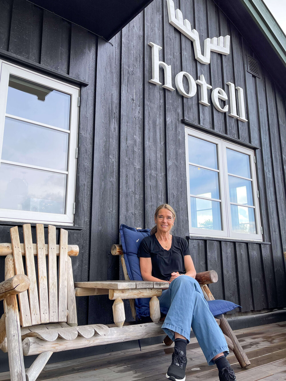 Jannicke eier og driver av Skåbu Fjellhotell sitter på den hyggelige uteplassen utenfor hotellet i en stol. 