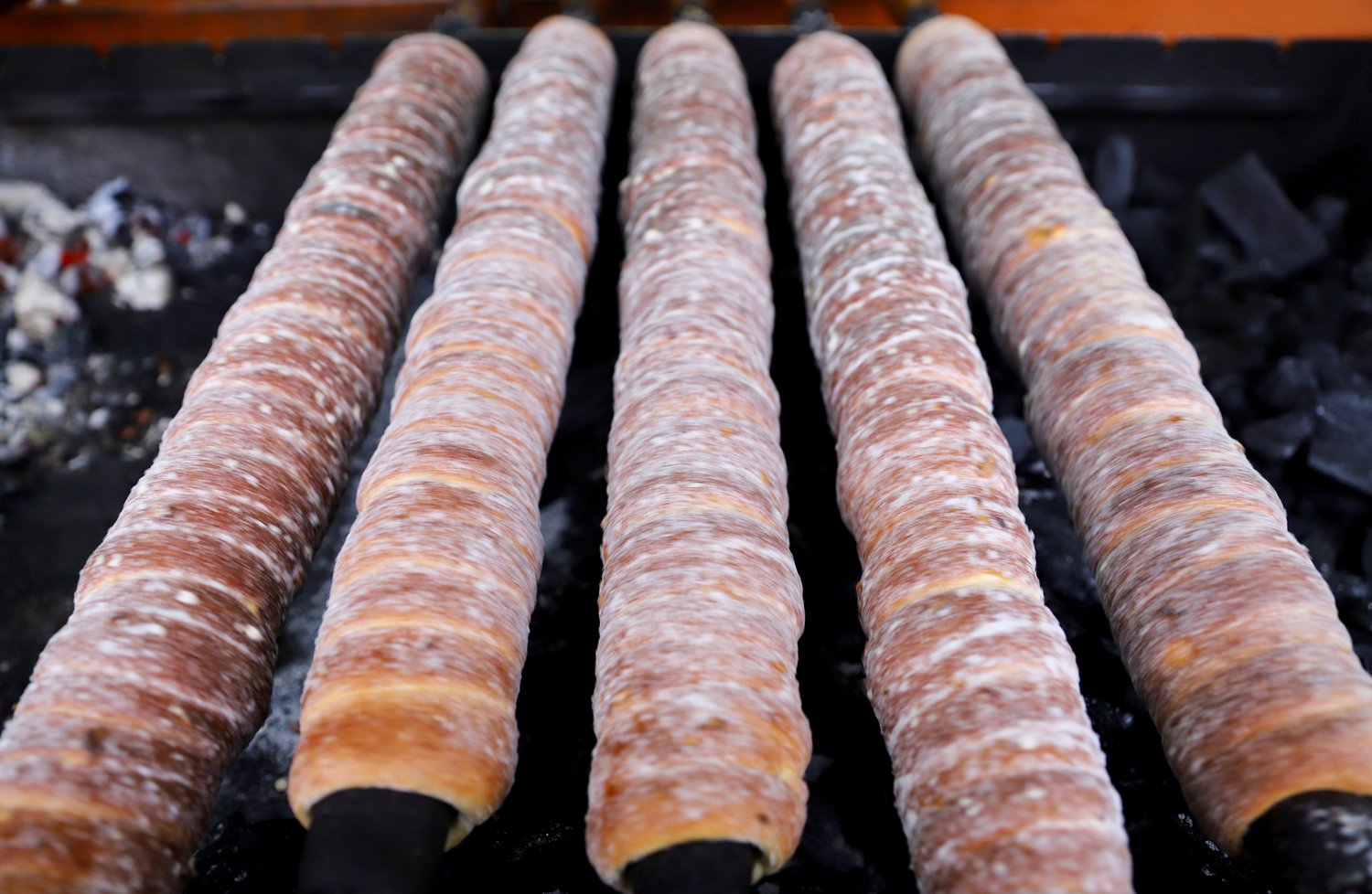 Trdelnik fem ruller som stekes på grill over kull. 