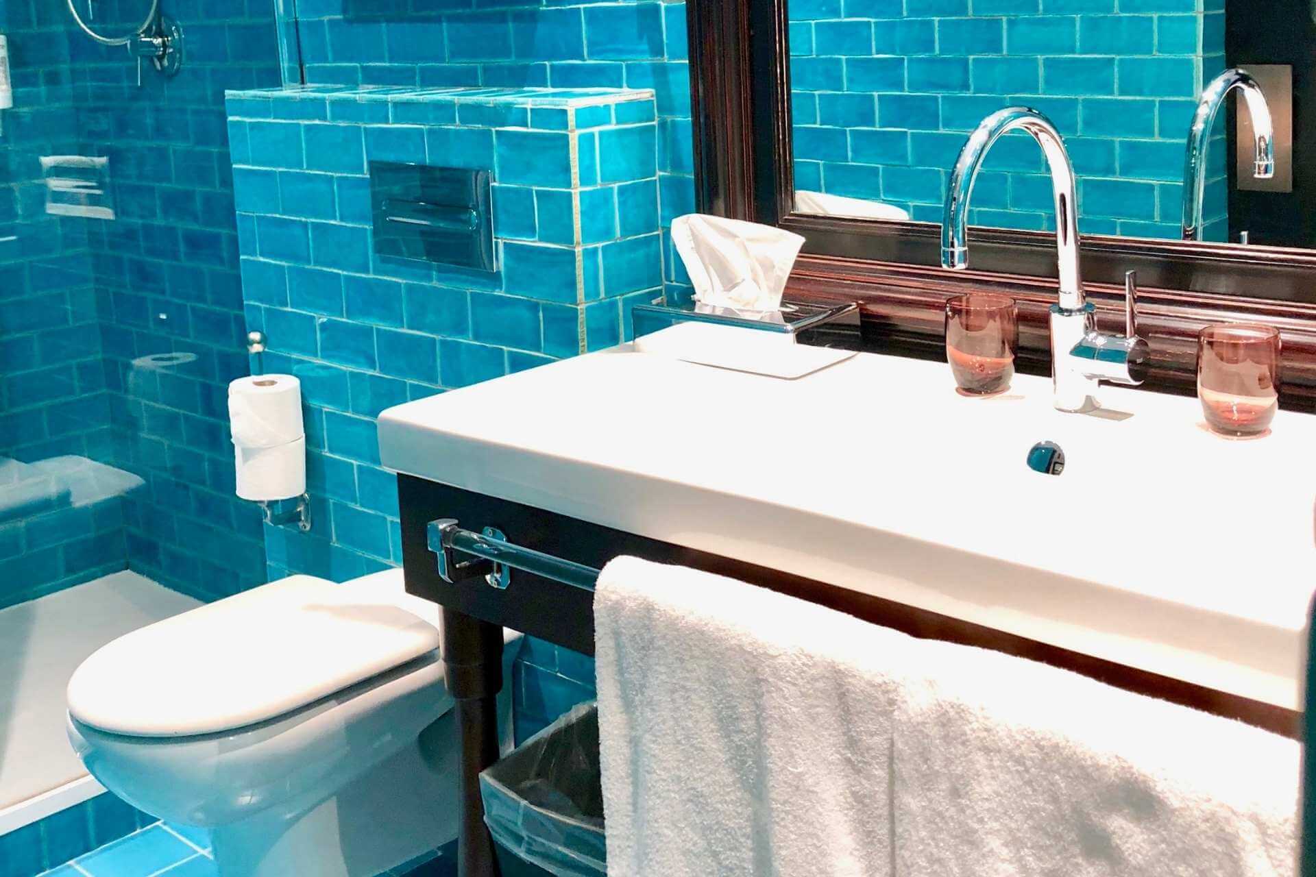 Bad p&aring; hotell i Barcelona med karakteristiske turkise fliser og moderne detaljer.