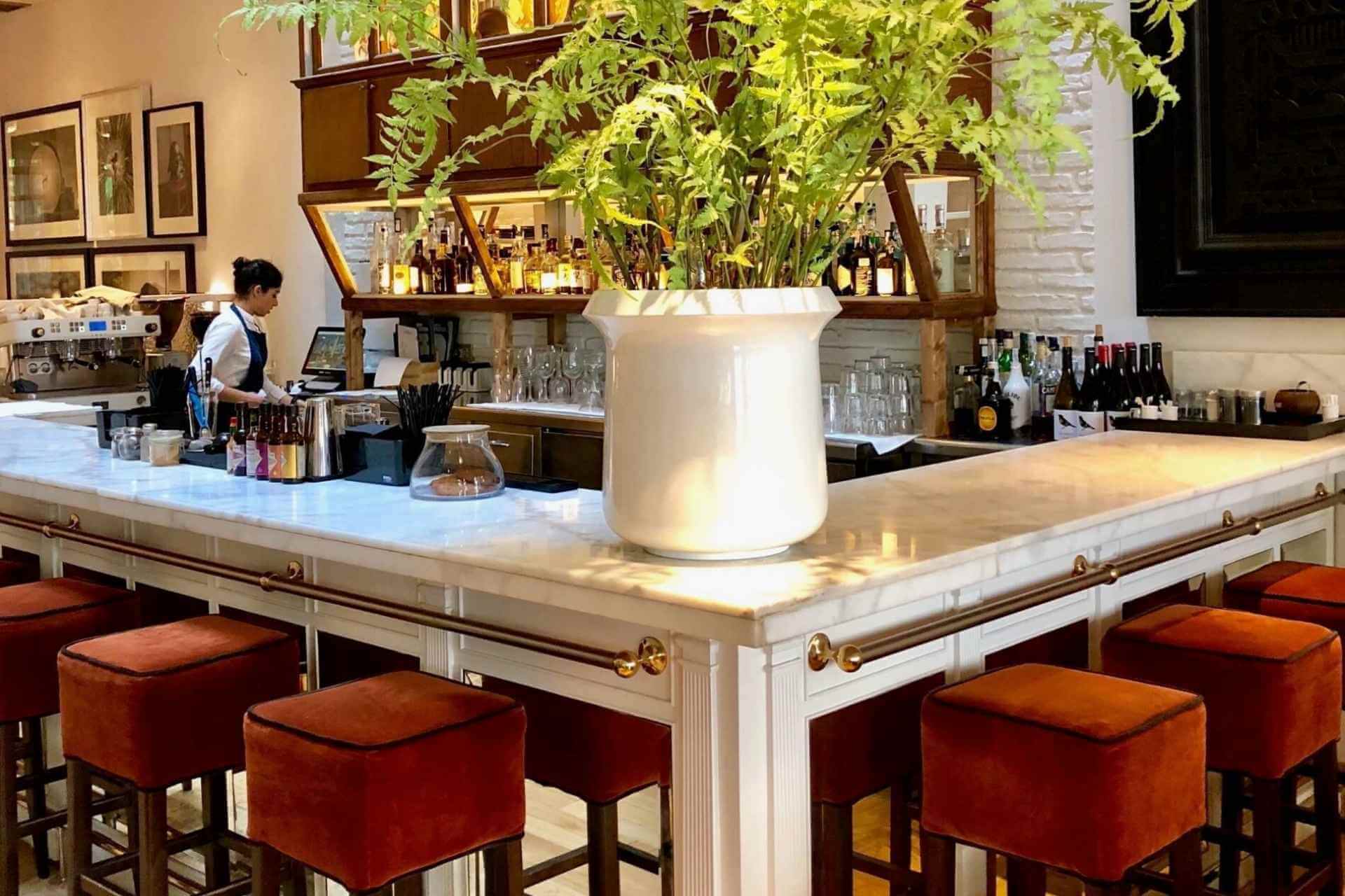 Lobbybaren p&aring; Pulitzer i Barcelona med klassisk interi&oslash;r og gr&oslash;nn beplantning.