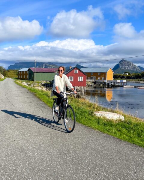 Blid turist på sykkel på Helgelandskysten. Bak ser du hotellet Støtt.