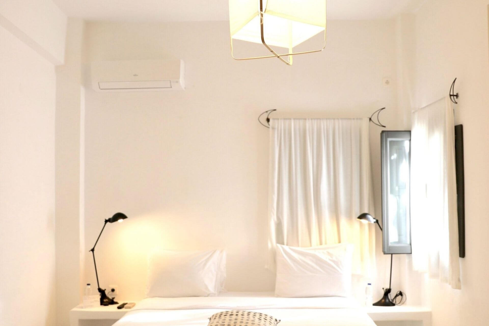 Soverom i minimalistisk kykladisk stil med hvite flater og mykt lys p&aring; Santorini