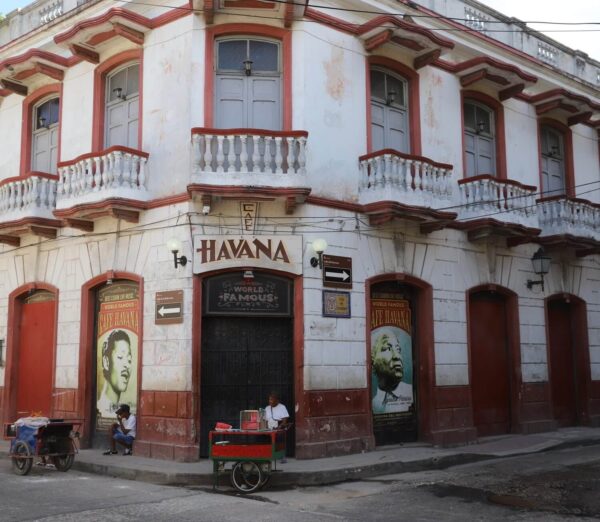 Fasaden på Café Havana Cartagena på dagtid. To selgere venter på kjøpere med sine trillevogner.