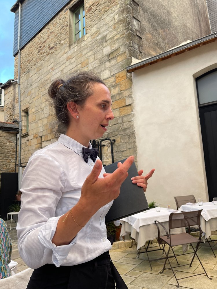 Fransk servitør forklarer menyen på restaurant i Bretagne. 