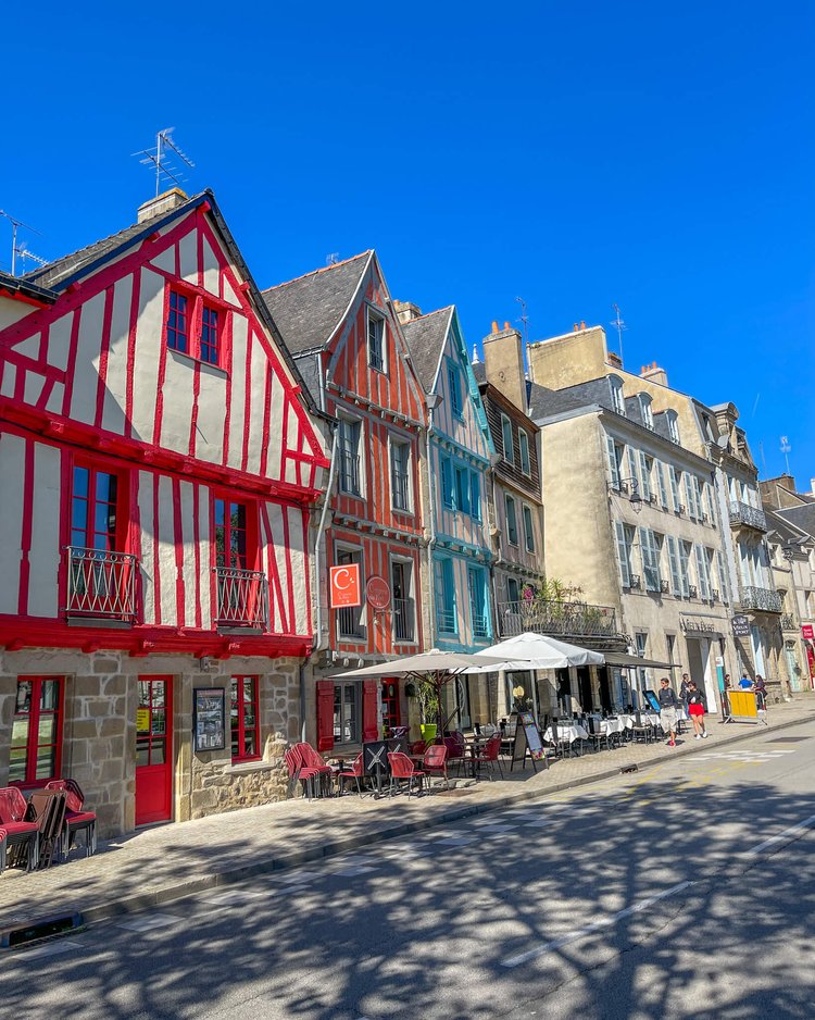 Vannes ikoniske byndingsverkhus, i rødt, turkis og rosa. Uterestaurant og klar blå himmel. 