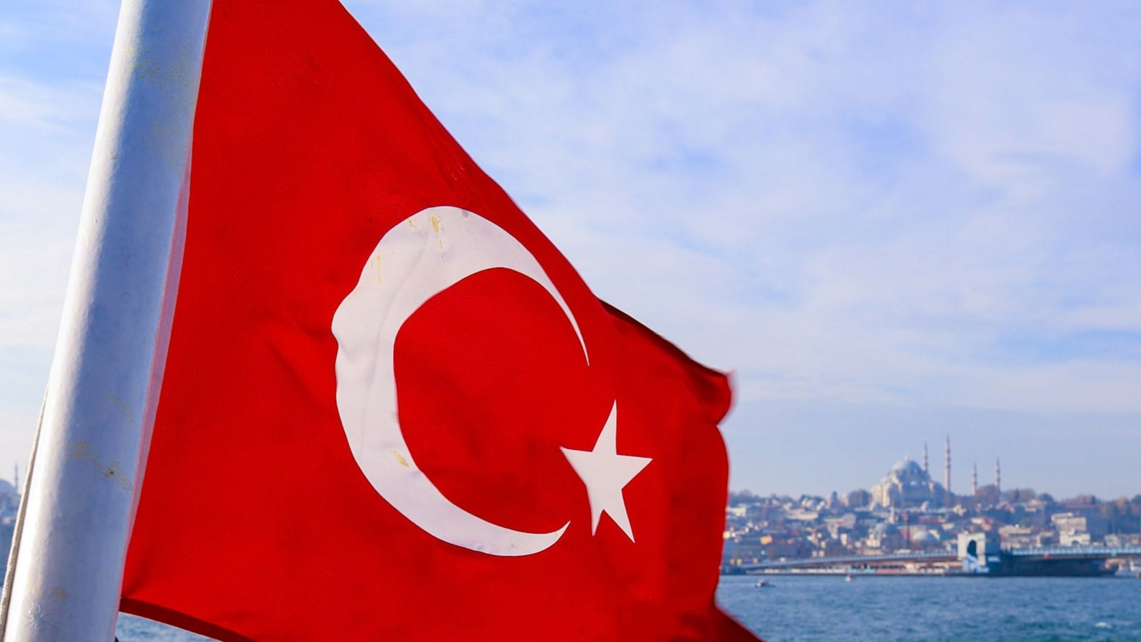 Tyrkias flagg vaier i vinden etter båten på Bosporus. I bakgrunnen skimtes byen Istanbul med Hagia Sophia.