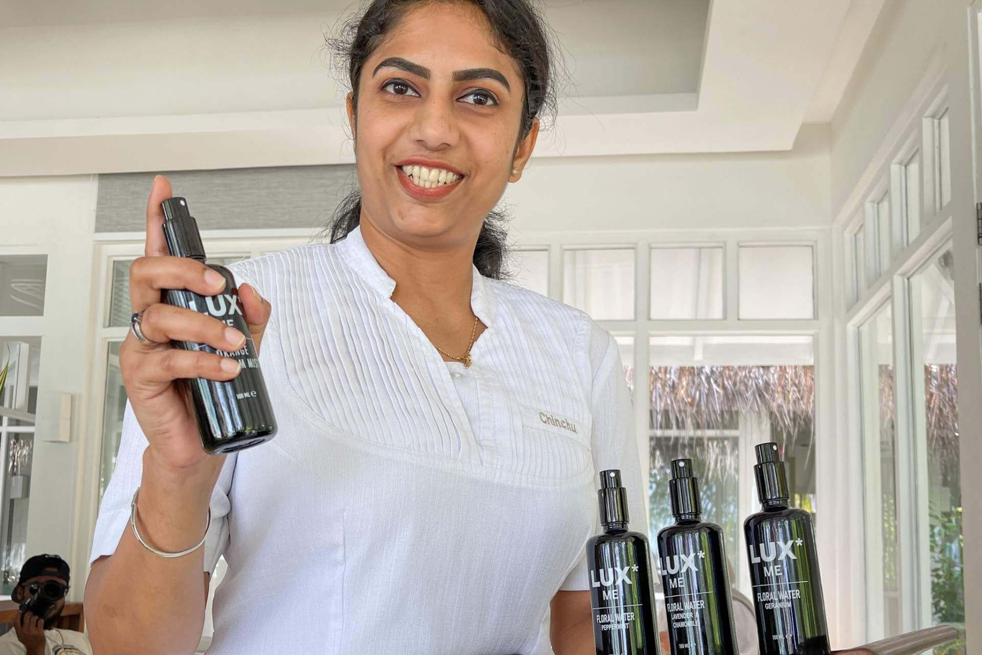 Spa og velv&aelig;re smilende terapaut som viser frem ulike oljer for massasje. 