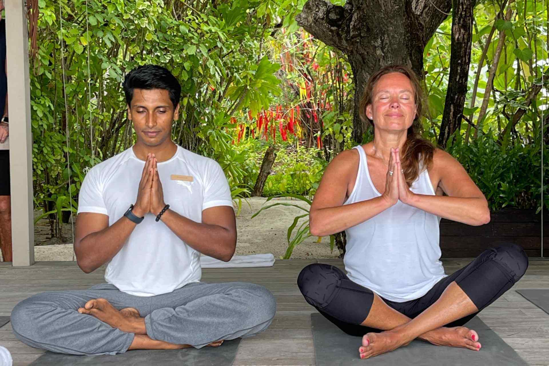 Yoga ved stranden instrukt&oslash;r og resortgjest praktiserer 