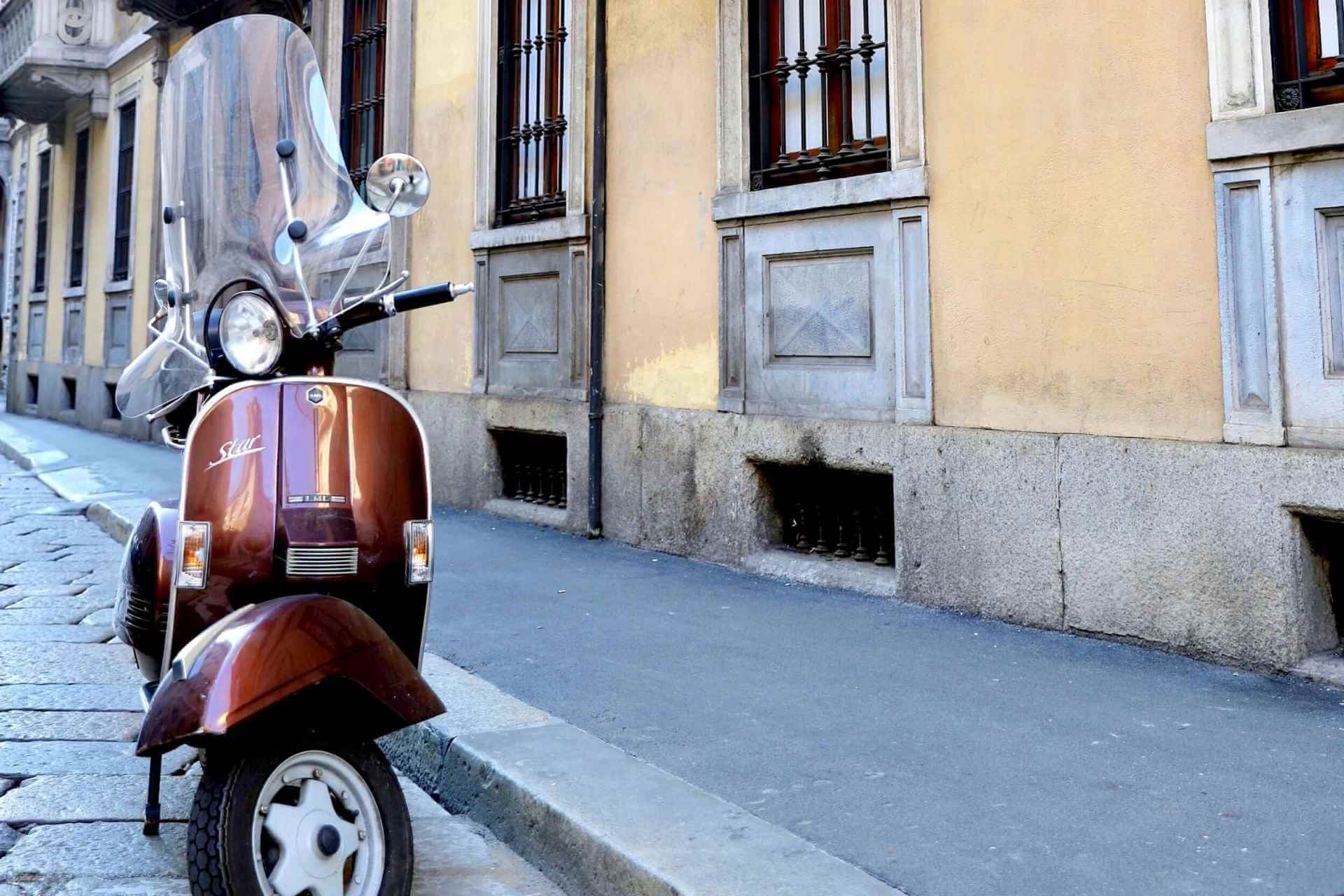Brun Vespa parkert i en gate i Milano. 