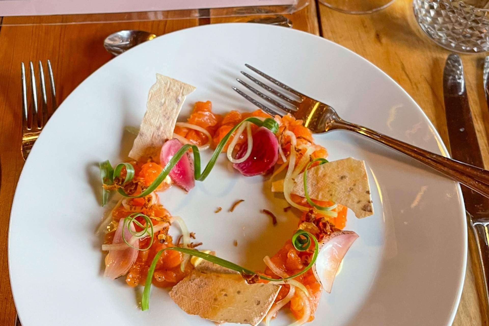 Elegant anrettet rett med lokale råvarer servert i restaurantmiljø.