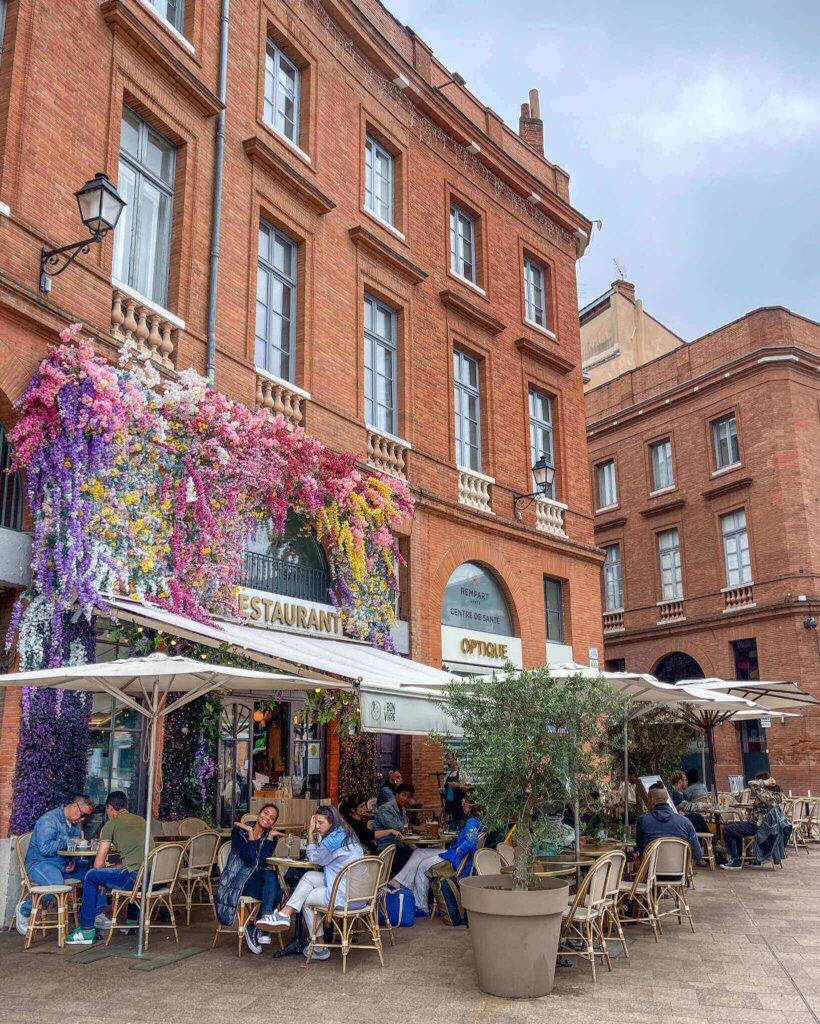 Kafe i koselig mursteinsbygg i Toulouse . Den rosafargede mursteinsvegger er kledd med blomster.