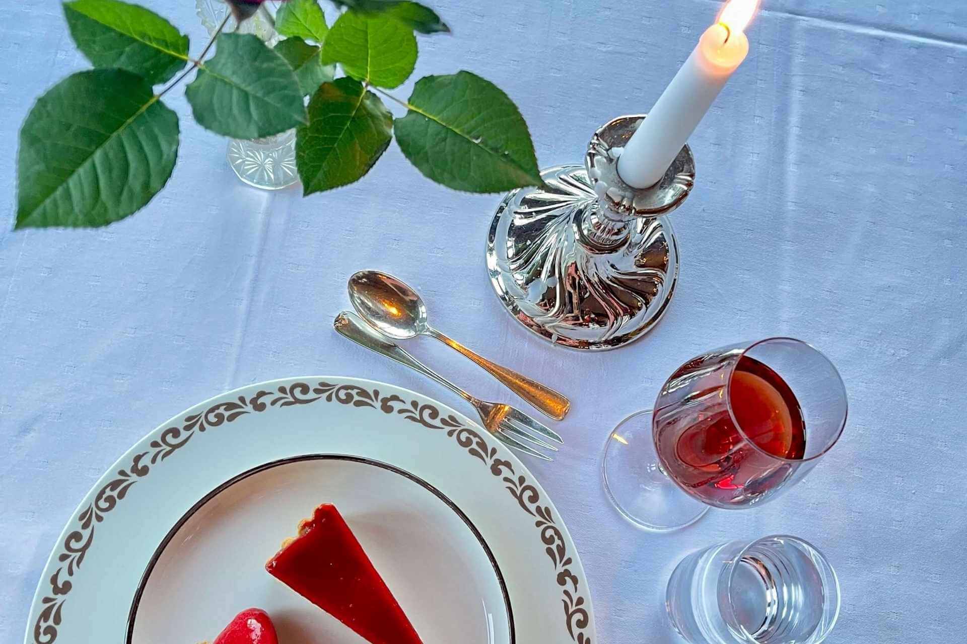 Dessert og borddekking under middag. Lysestake og bestikk i s&oslash;lv. Gammeldags porselen til servise. 