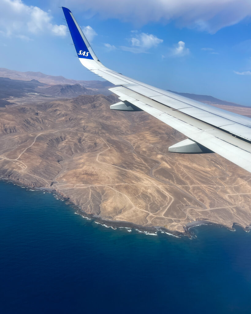 Et SAS fly flyr over Fuerteventura. Fra flyvinduet ser du Kanariøya og havet. 