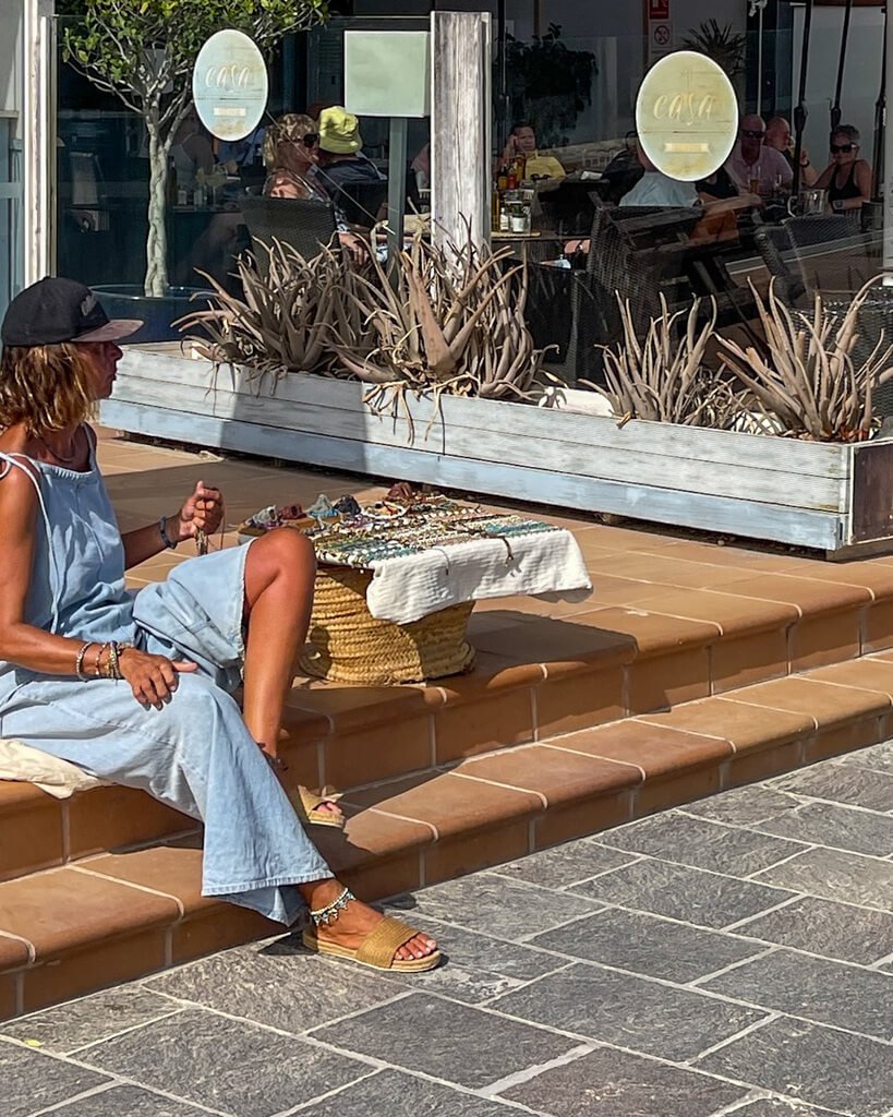 En dame selger håndlagede smykker på gaten i Corralejo. 