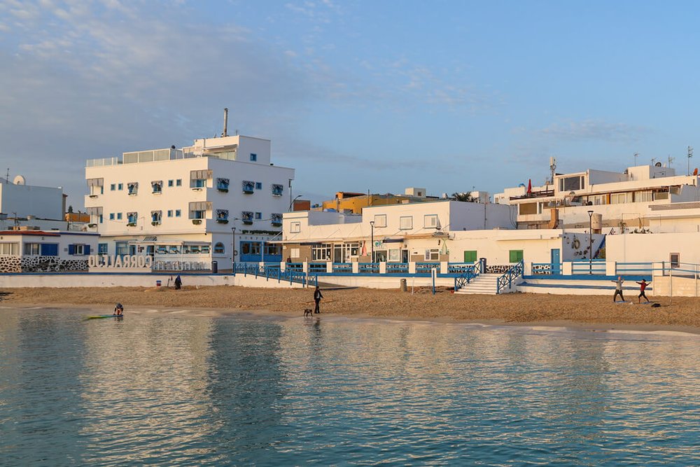 Bystranden i Corralejo strand en tidlig morgen. Noen gjør yoga andre lufter hunden.