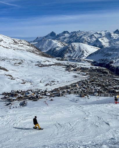 En snowboardkjører som kjører nedover bakken mot alpelandsbyen. 