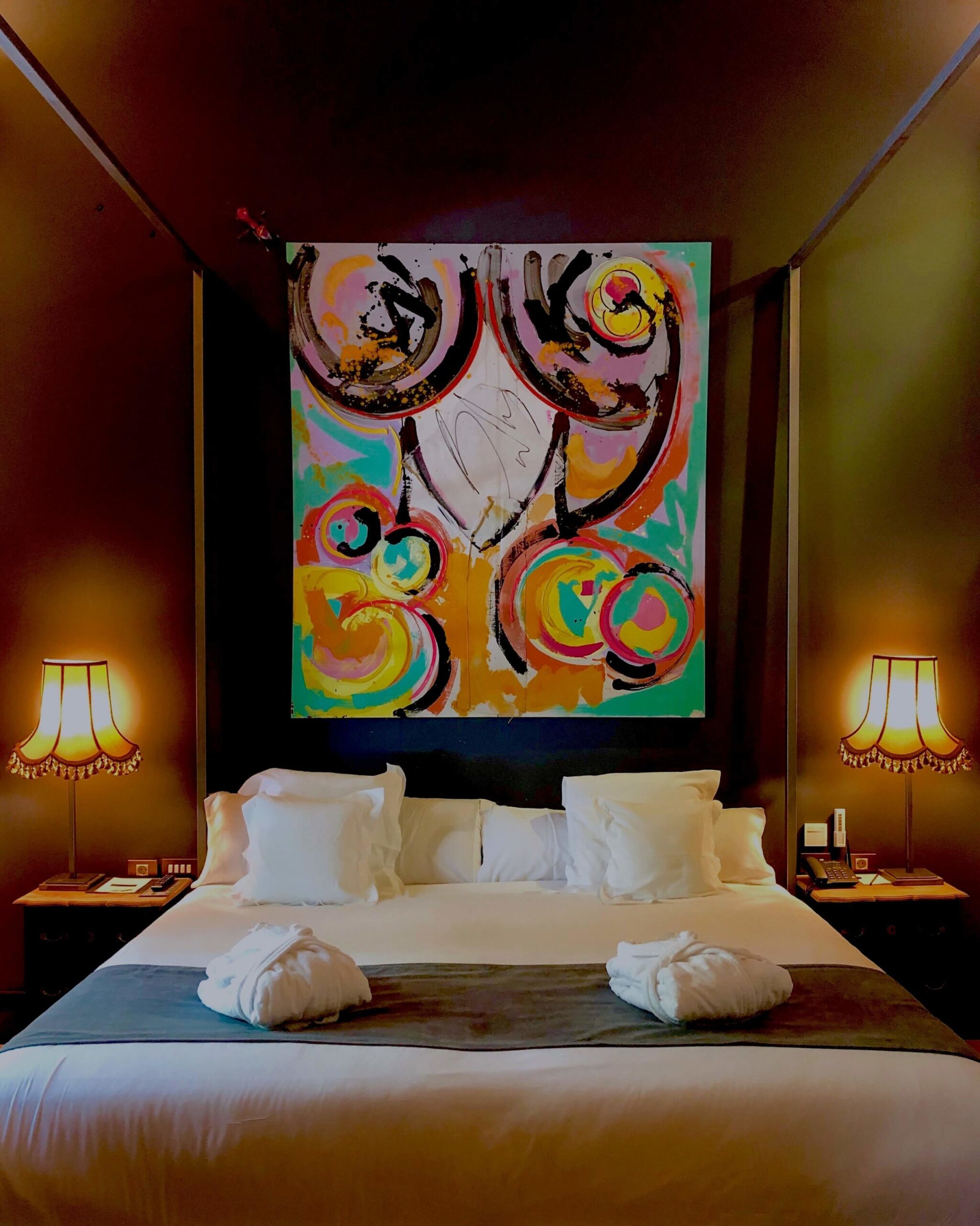 Hotel Lobby bedroom with double bed and a huge painting over the bed. 