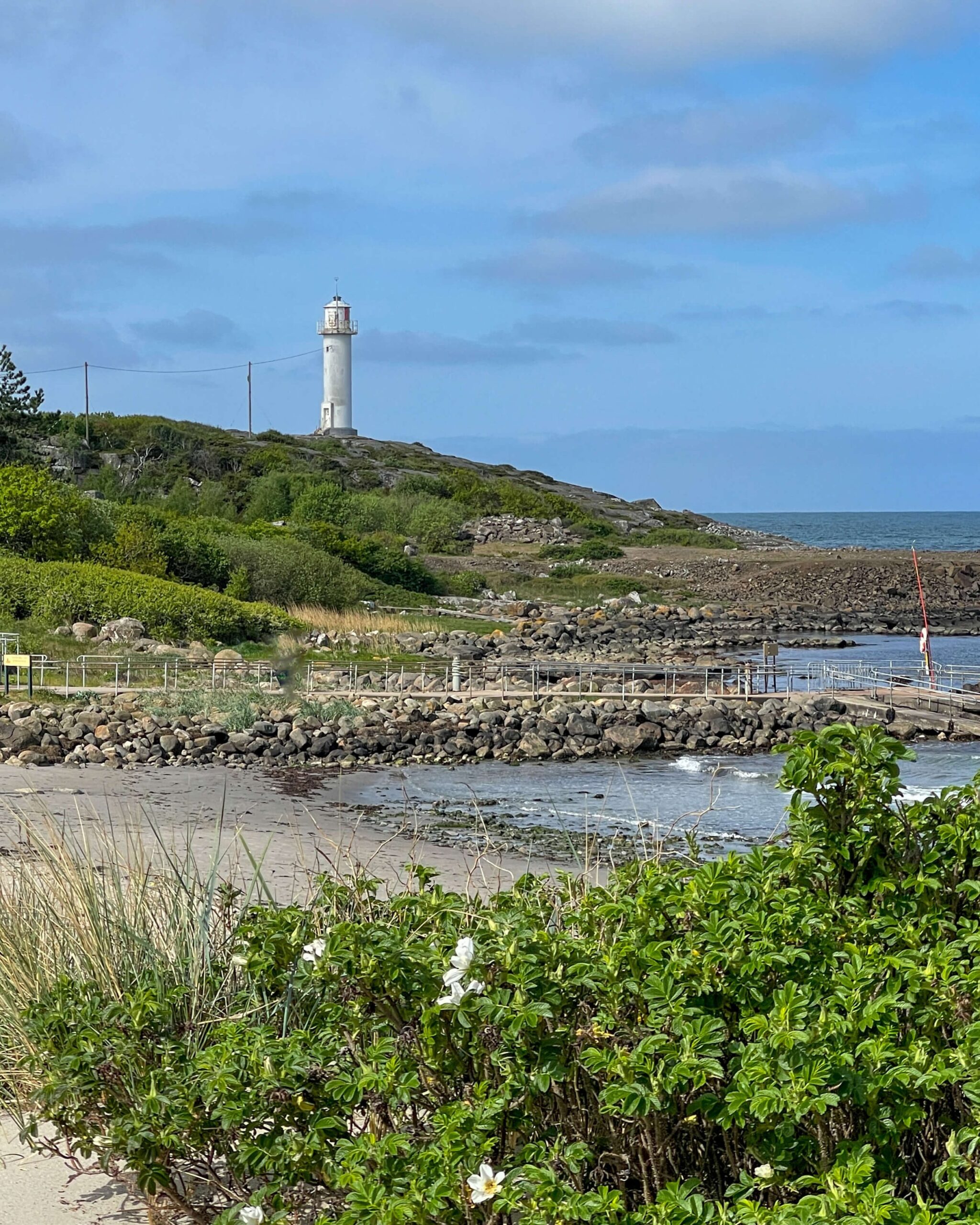 Subbe fyr i Lille Apelviken. I forgrunnen nyperoser, stranden og havet. 