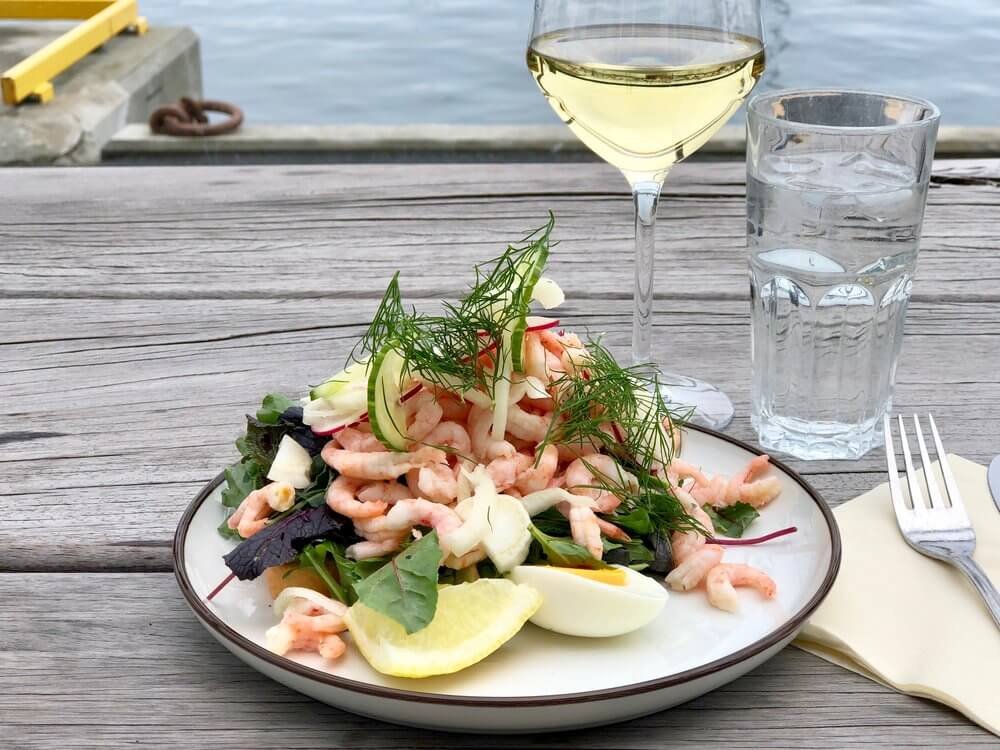 Rekesmørbrød servert med egg, agurk, salat og hvitvin på uteserveringen på restaurant Bryggerikaia i Bodø. 