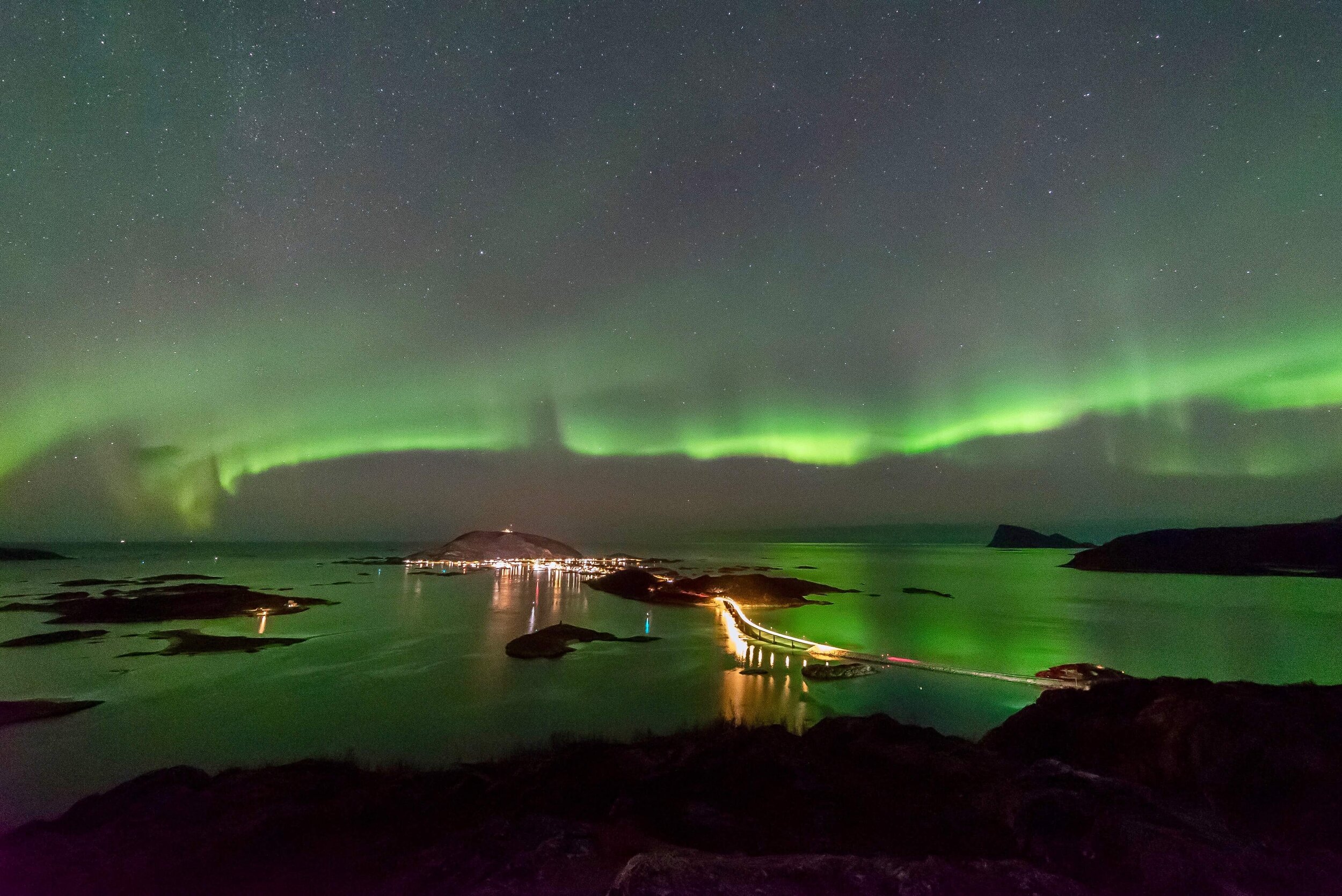 Sommaroy Nordlys som skinner på veien, øyene og broene. 