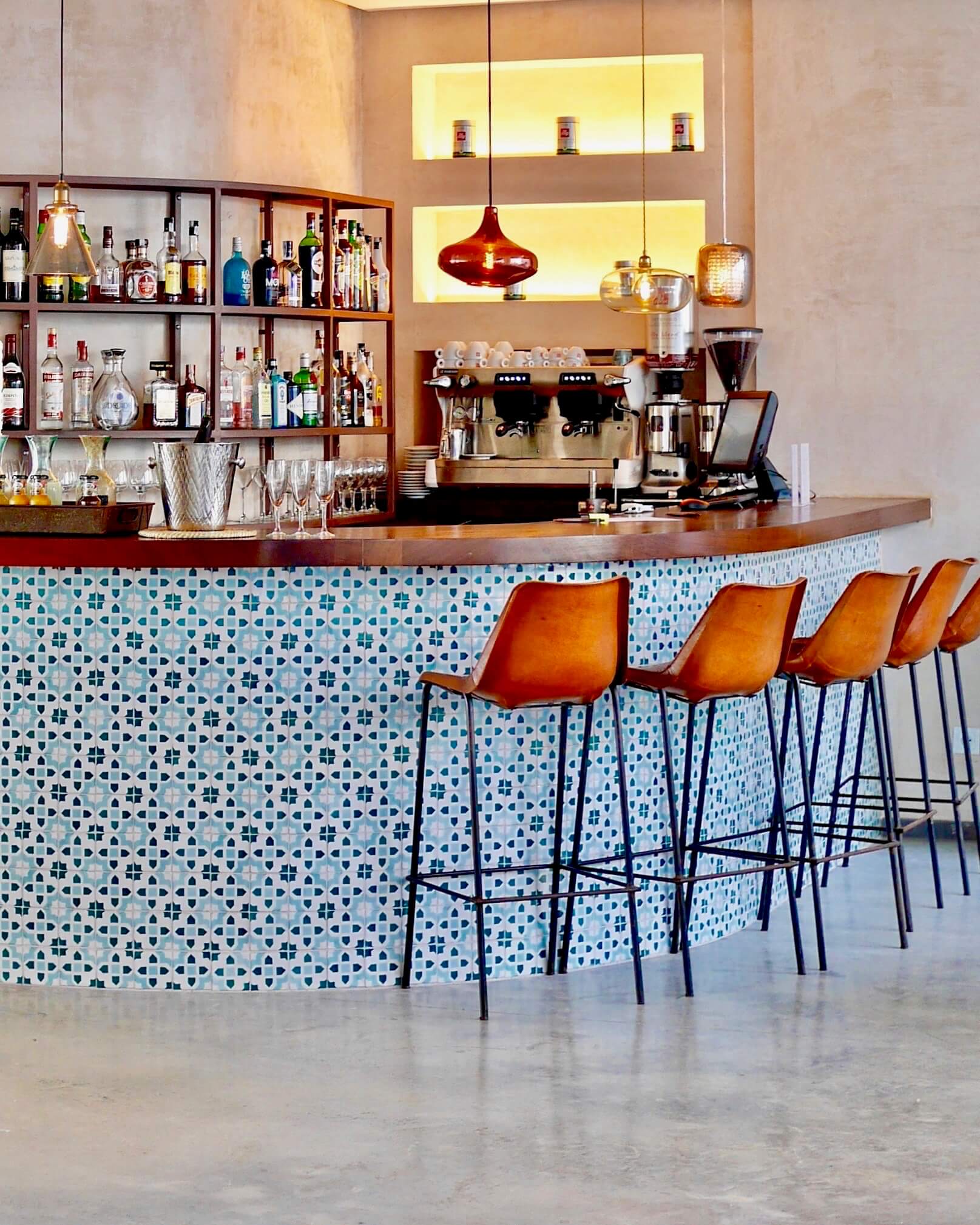 La Residencia Tarifa bar with brown high chairs and moroccan tiles in combination with concrete. 