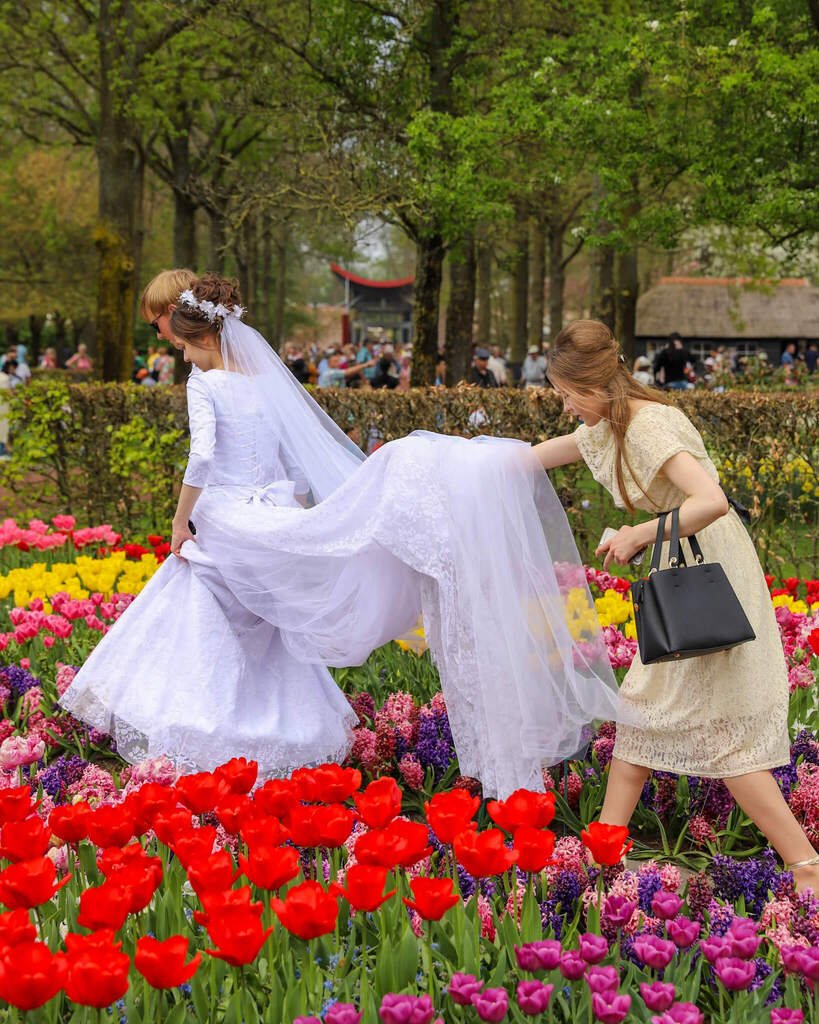 Et brudepar i Keukenhof omgitt av et hav av tulipaner og andre fargerike blomster i blomsterhagen.