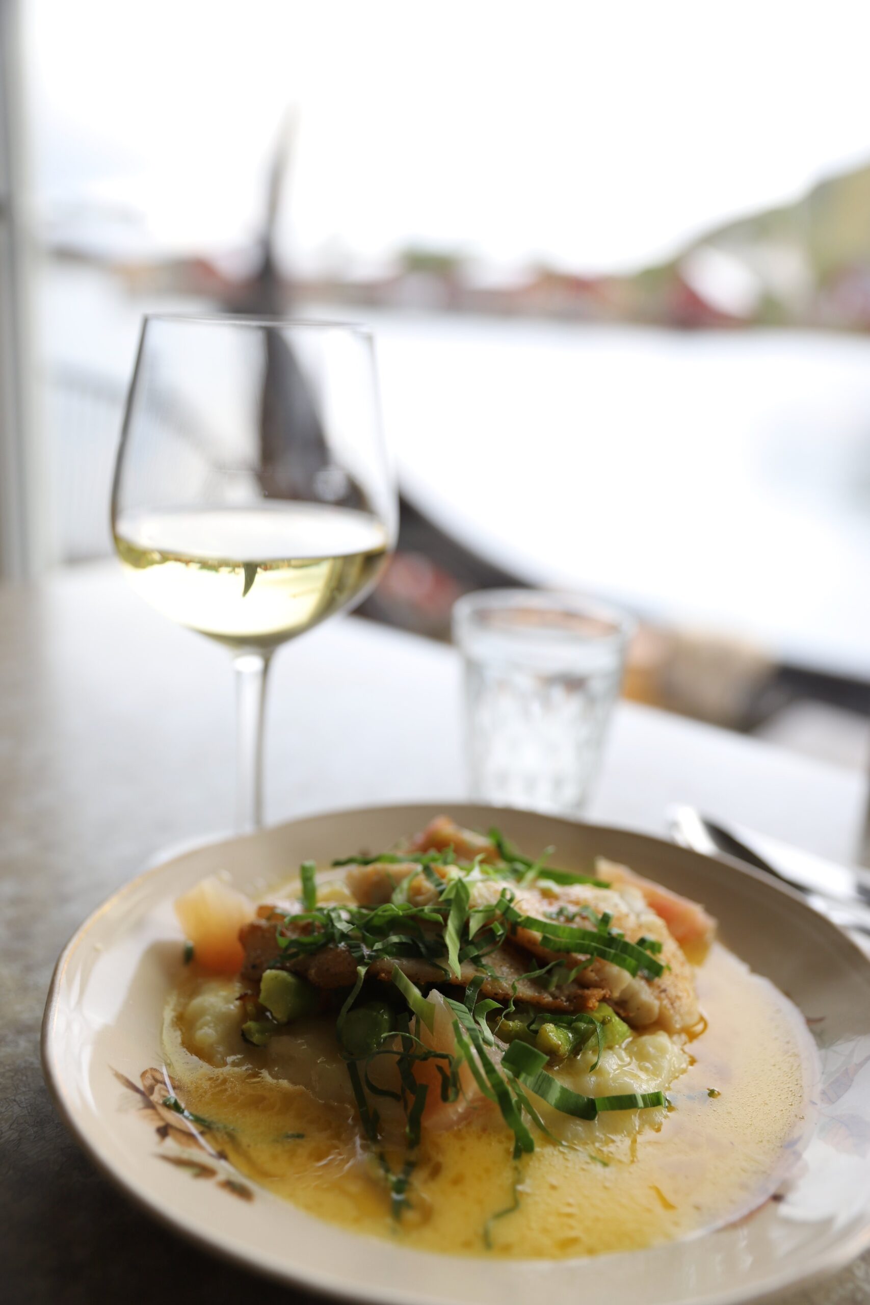 Kortreist fisk servert med hvitvin og utsikt over havet på Solsiden restaurant Lofoten i Ballstad.