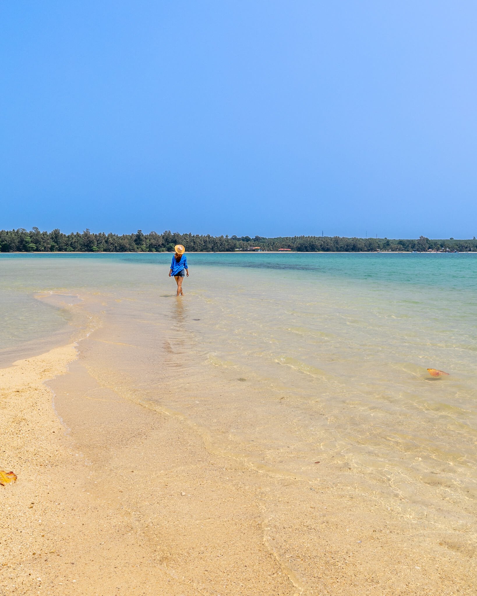 En flott sandstrand med turkist hav og lys sand. Her går jeg tur på stranden med blå short og blå skjorte, like blått som himmelen.