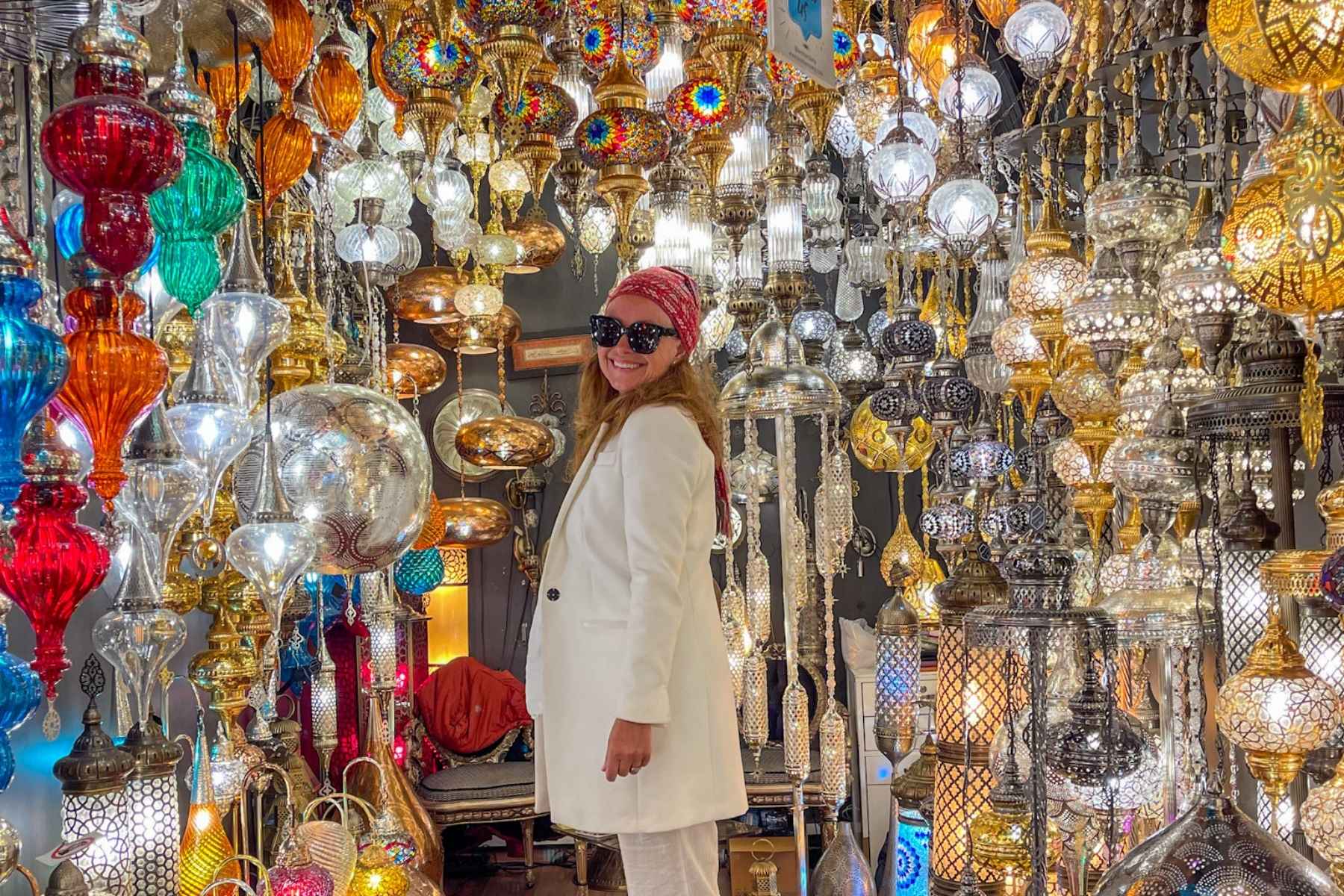 Smilende dame poserer ved fargede lamper på Grand Bazar i Istanbul. 