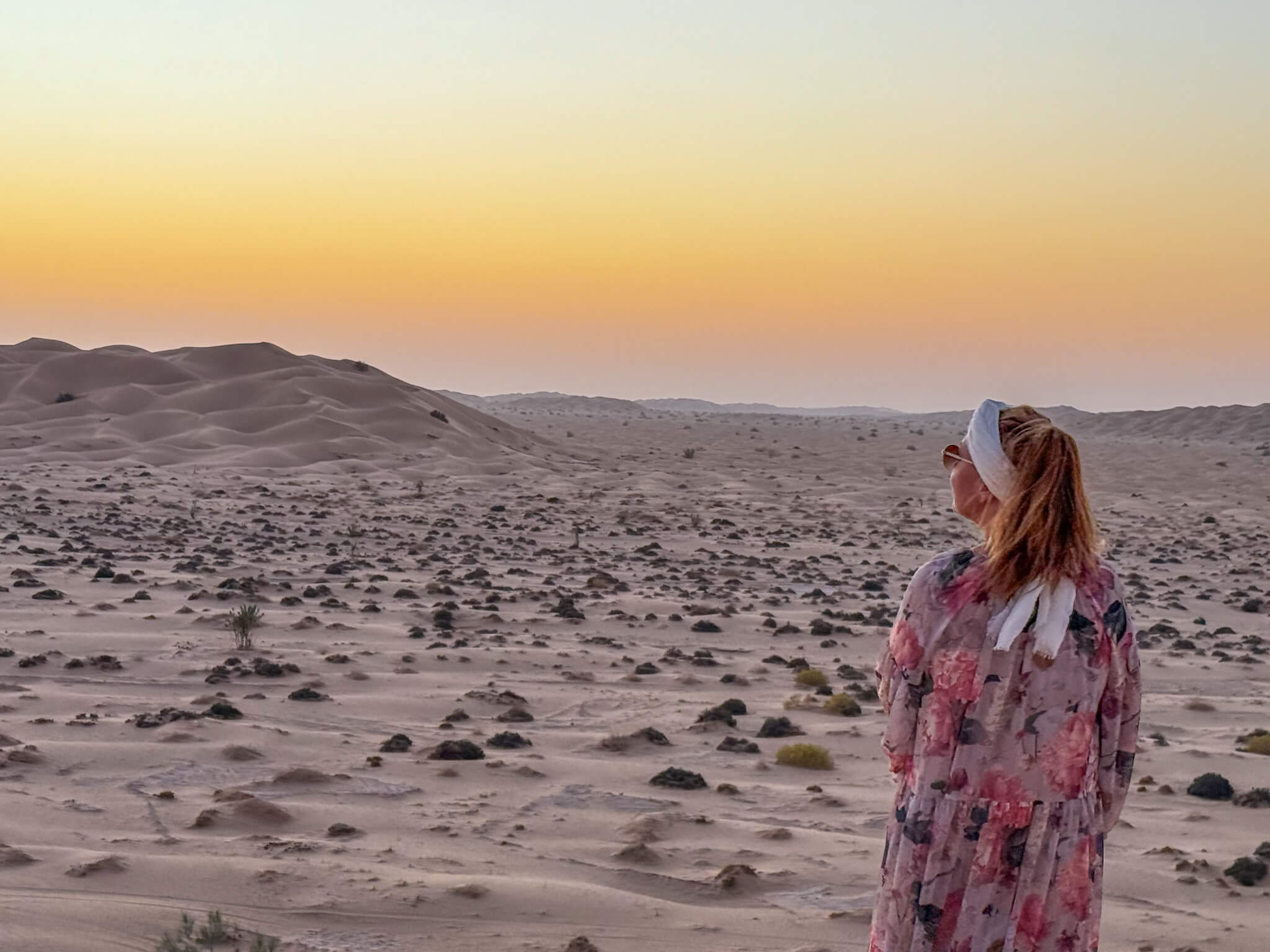 Solnedgang i Empty Quarter Desert I Oman. Jeg ser solen gå ned med. På meg har jeg blomstrete kjole. 