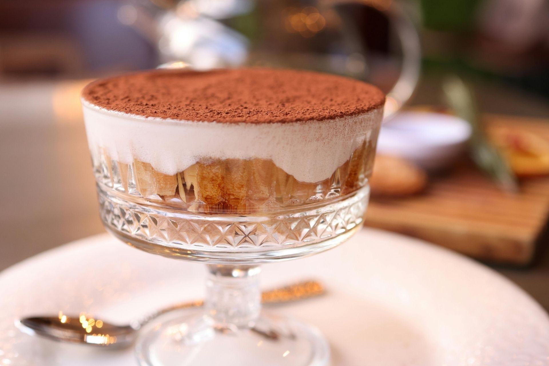 Tiramisu servert i et krystallglass, lagvis med mascarponekrem og fingerkjeks, toppet med kakao.
