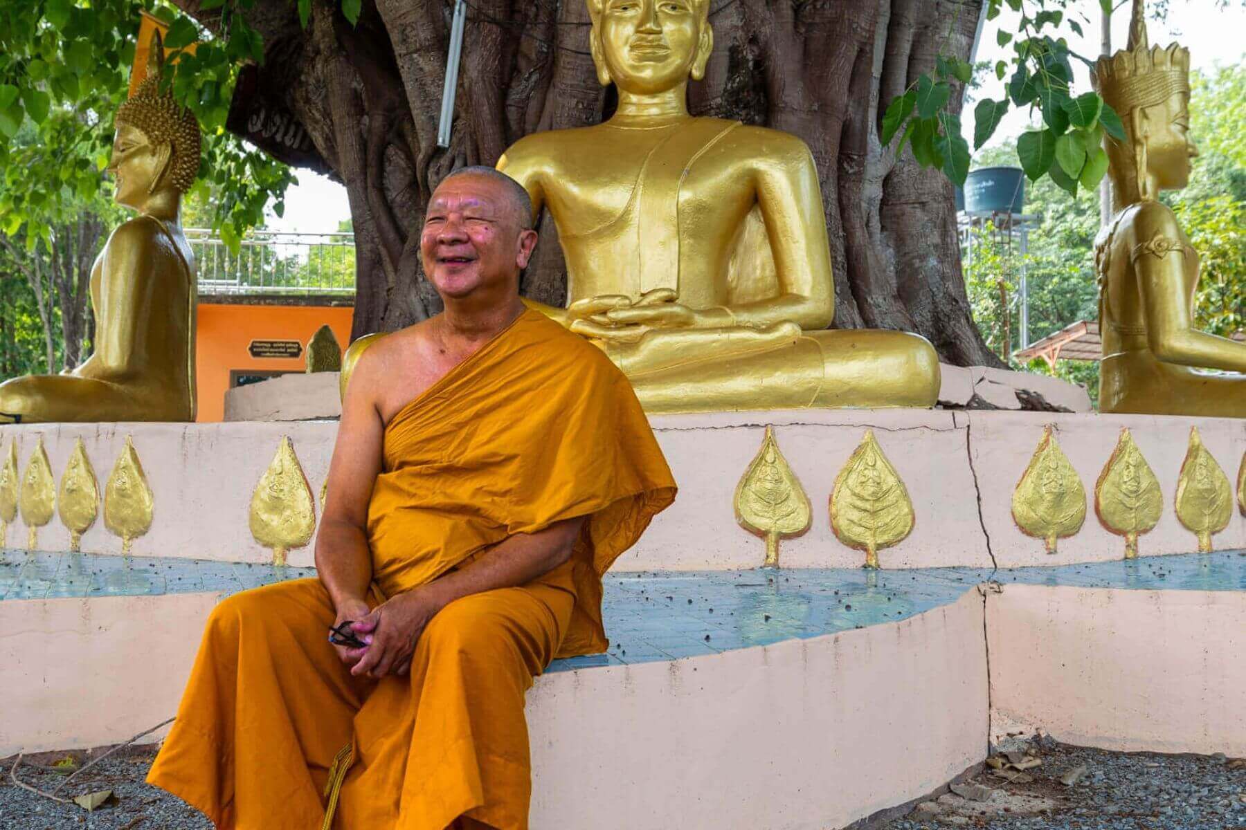 Buddhistisk munk foran gylne Buddha-statuer p&aring; Koh Mak