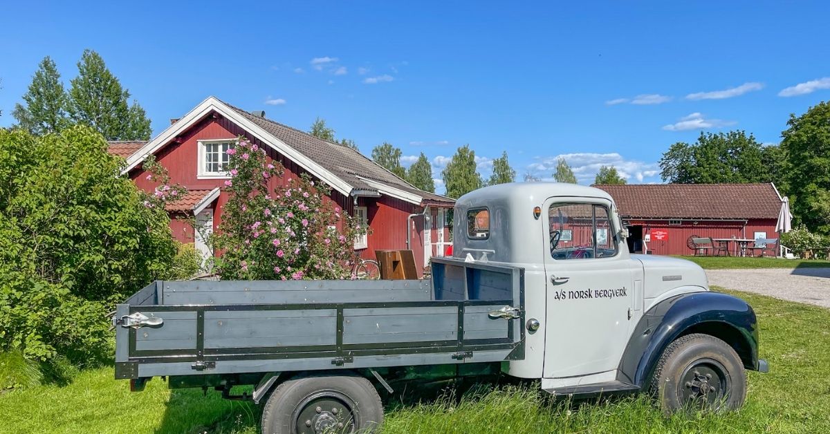 Arbeiderboligene Ulefoss en gammel lastebil og rødmalte trehus en sommerdag.