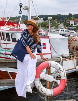 Dame i maritim stil foran gammel koselig fiskebat på Telemarkskysten.