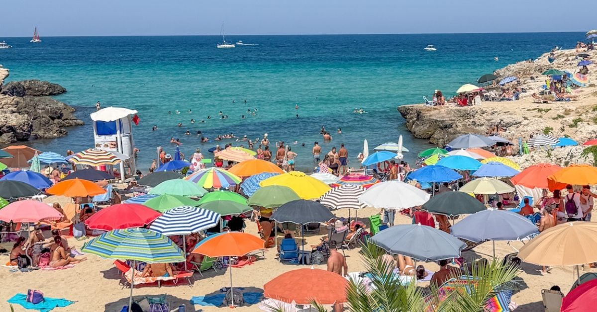 Bystrand i Monopoli Puglia, full av badegjester og fargerike parasoller.