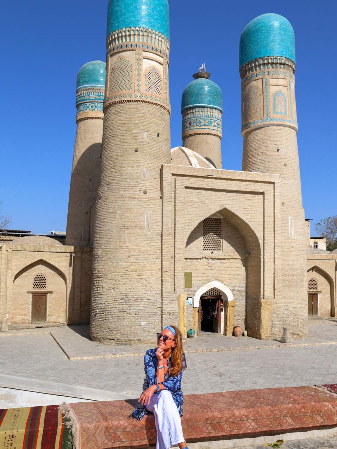 Merete Moen foran Chor Minor i Bukhara, Usbekistan – et ikonisk landemerke med fire blå kupler og utsmykninger som forteller historien om Silkeveien.