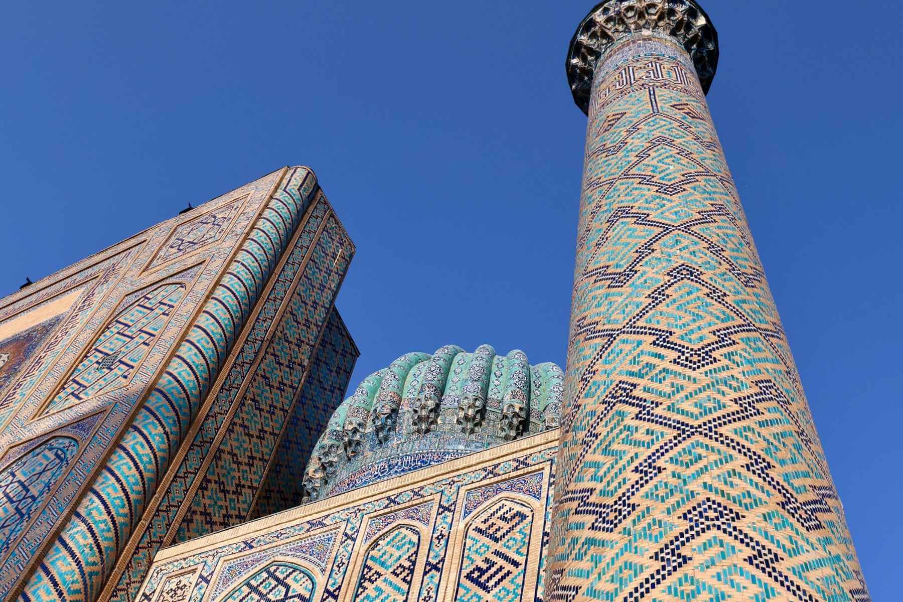 Registan-plassen i Samarkand, Usbekistan – et praktfullt kompleks med mosaikkdekkede madraser som glitrer i blåtoner under ettermiddagssolen.