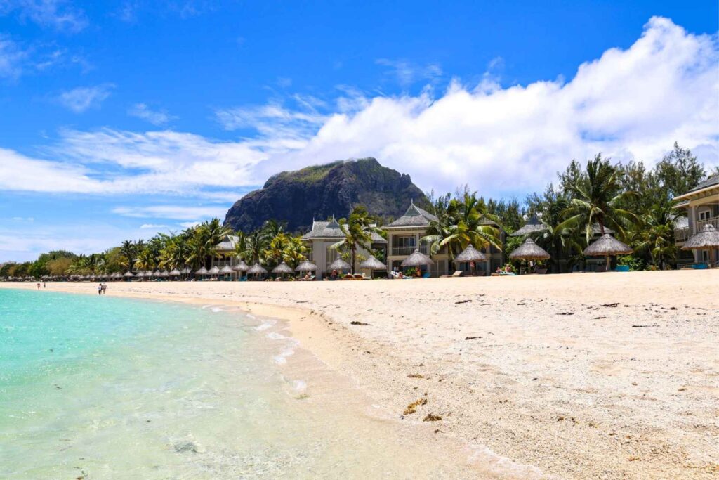 Stranden foran St. Regis Le Morne med turkis vann, palmer og Le Morne-fjellet i bakgrunnen på sørvestkysten av Mauritius.
