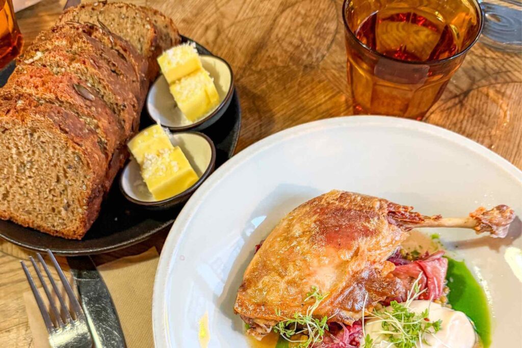 Mørkt estisk rugbrød servert med smør og kyllingrett på restaurant i Tallinn.