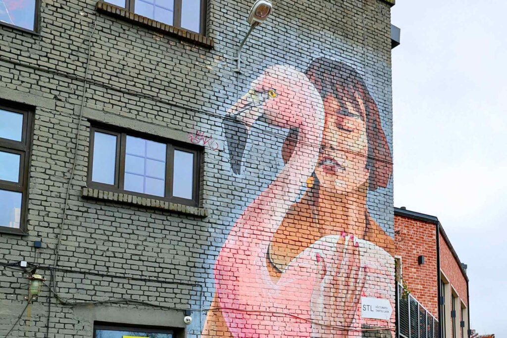 Streetart i Tallinn: veggmaleri av en kvinne med roas flamingo malt på murfasade, et av områdets ikoniske kunstverk.