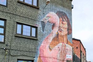Streetart i Tallinn: veggmaleri av en kvinne med roas flamingo malt på murfasade, et av områdets ikoniske kunstverk.