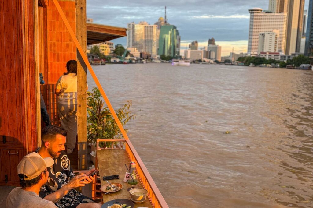 Middag ved Chao Phraya-elven i Bangkok med utsikt mot byens skyline i solnedgang.