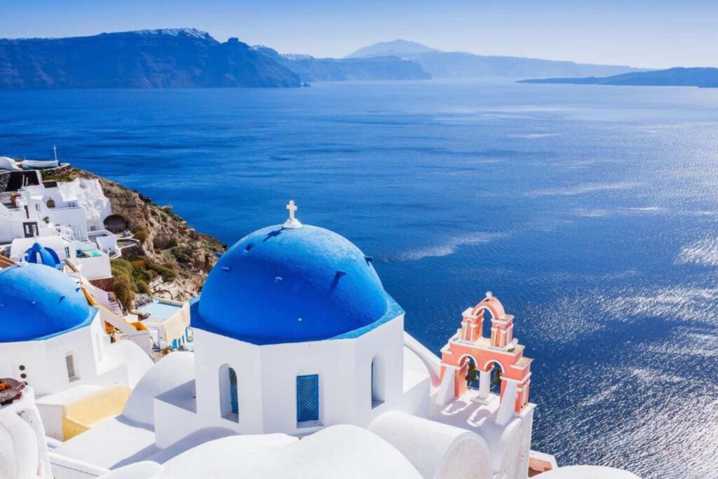 Bl&aring; kuppel og hvite hus p&aring; Santorini med utsikt over Egeerhavet i Kykladene, Hellas.
