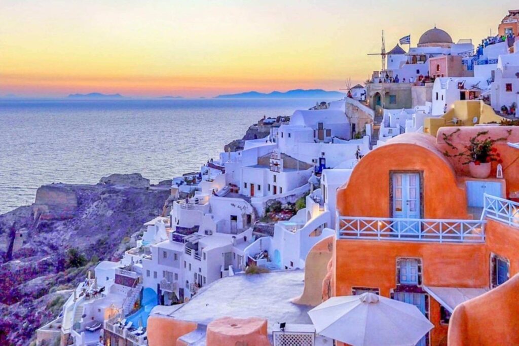 Solnedgang over Oia p&aring; Santorini i Hellas med hvite hus og utsikt mot havet i.