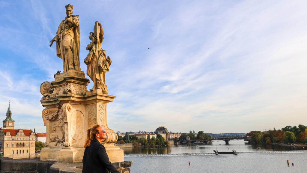 Barokke statuer på Karlsbroen i Praha med utsikt over elven Moldau og byens historiske sentrum.