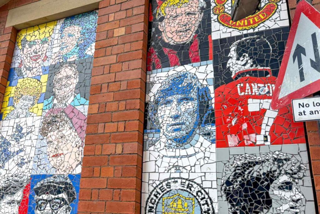 Mursteinsvegg med mosaikk med kjente fotballspillere i Manchester. 
