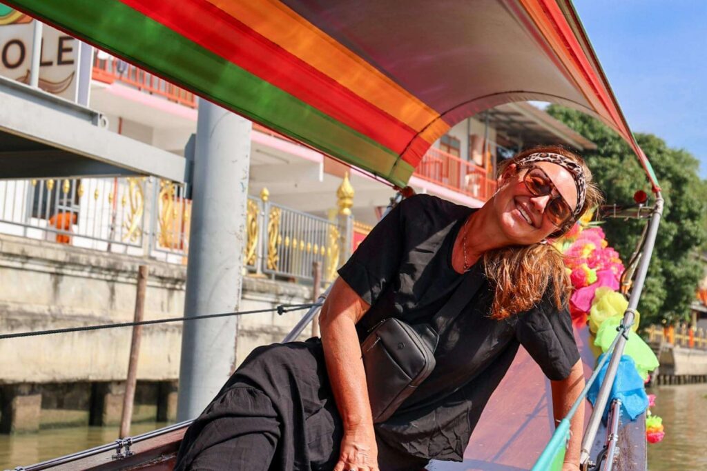 P&aring; b&aring;ttur i Bankgkok med stort smil og en crossbody reiseveske 