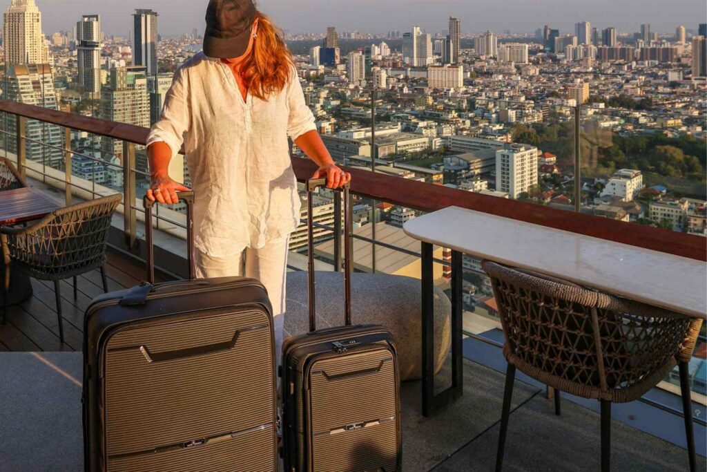 Pakke til storbyferie i Bangkok med stor sort hard koffert og kabinkoffert fra North Pioneer p&aring; rooftop med utsikt over byen