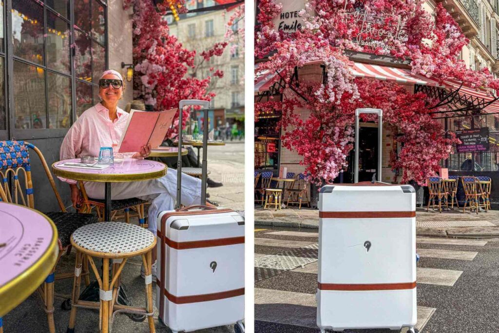 Smilende dame p&aring; kafe i Paris med hvit koffert. Kafeen er pyntet med rosa kirseb&aelig;rblomster