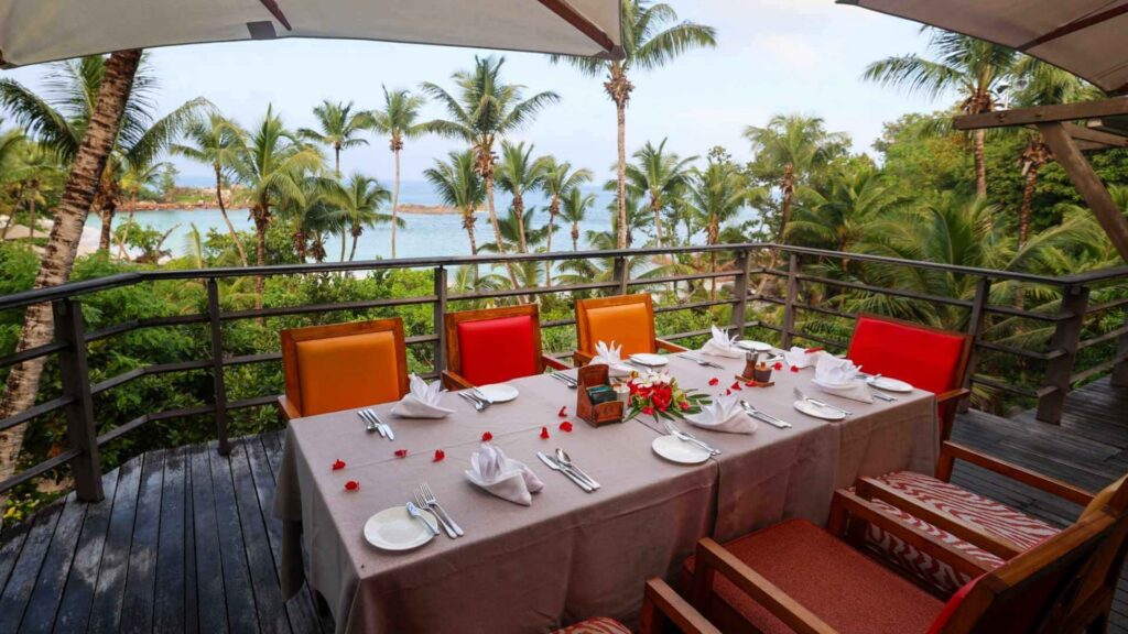 Bord i buffetrestauranten pent dekket. I bakgrunnen ses den tropiske hagen og havet.